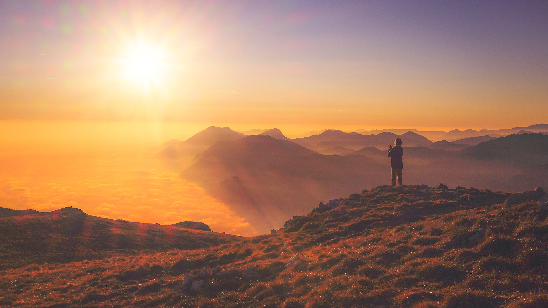 person-standing-on-mountain-at-sunset